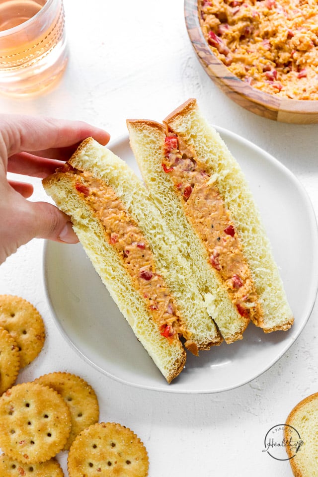 hand grabbing half of a pimento cheese sandwich