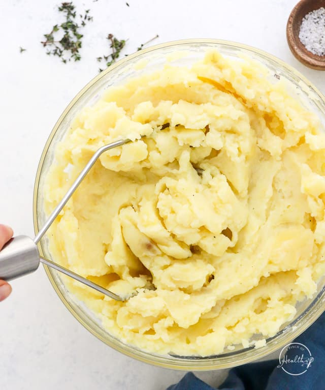 using potato masher to mash cooked potatoes