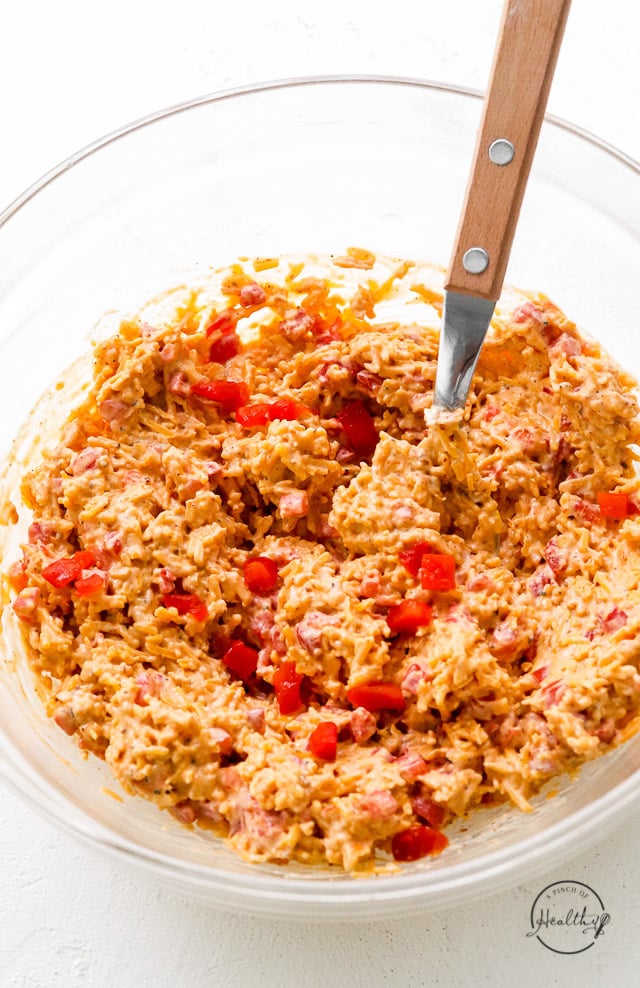 closeup pimento cheese being mixed in clear glass mixing bowl