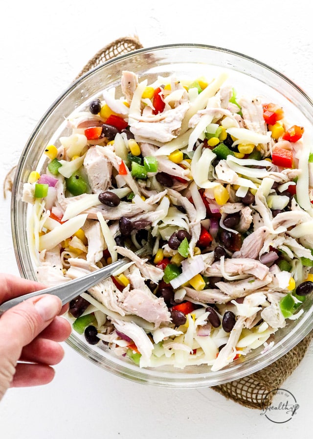 hand stirring chicken and veggies in clear glass bowl