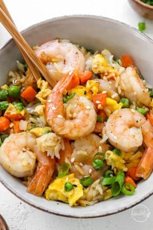 closeup of shrimp fried rice in bowl with chopsticks