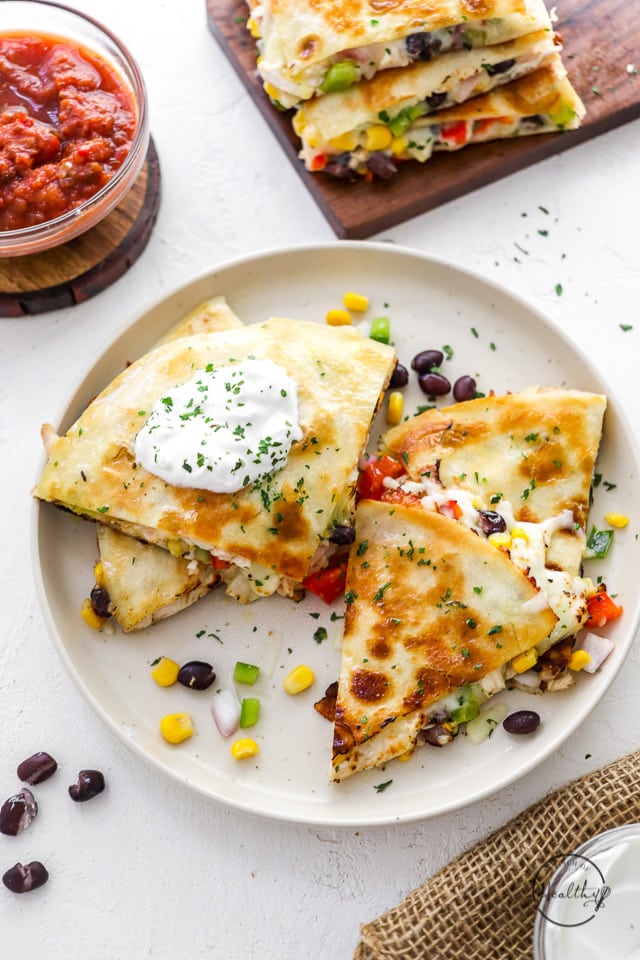 chicken quesadillas, sliced with sour cream on a white plate