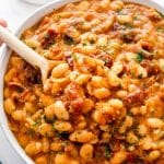Baked beans in a white serving bowl with spoon