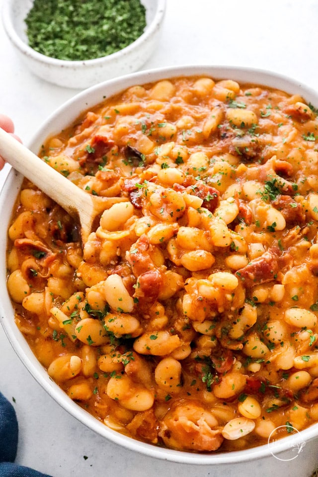 Baked beans in a white serving bowl with spoon