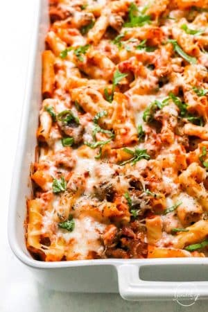 Closeup of baked ziti in white casserole dish