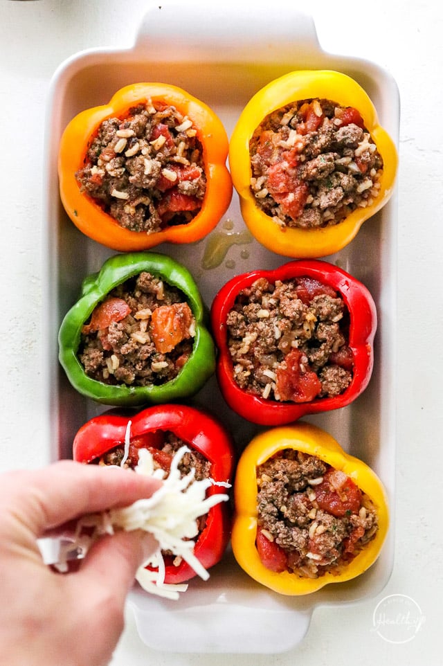 sprinkling cheese on stuffed bell peppers