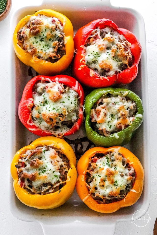 stuffed bell peppers with melted cheese on top in a baking dish
