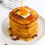 pumpkin pancakes with a pat of butter getting maple syrup poured on top