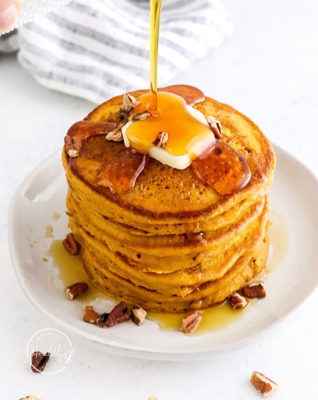 pumpkin pancakes with a pat of butter getting maple syrup poured on top
