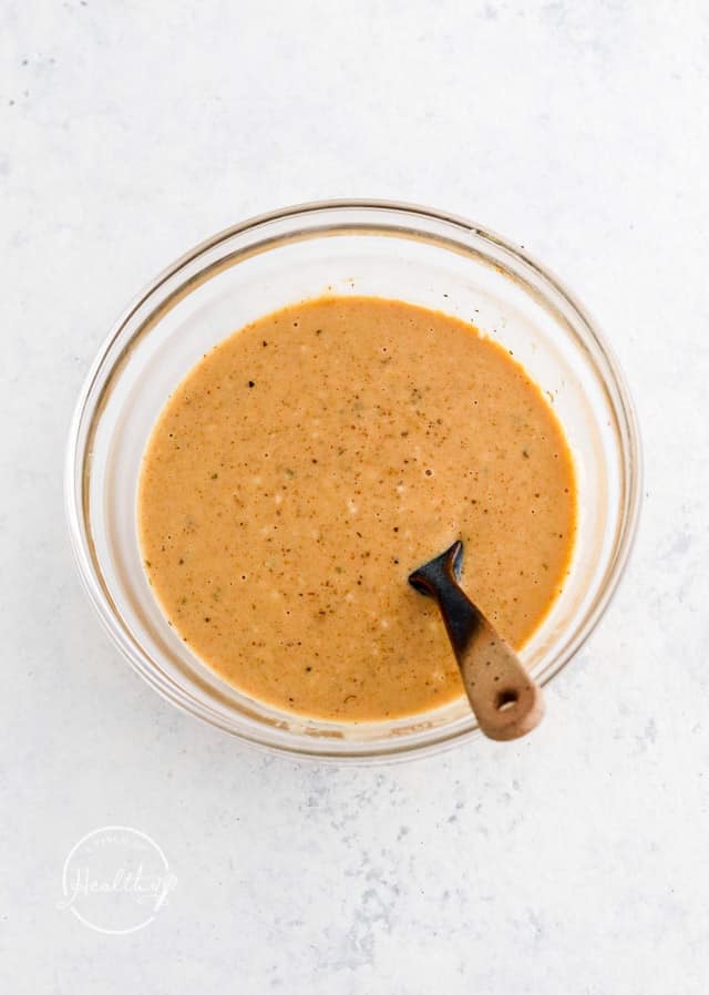 mixing sauce in a glass bowl with spoon