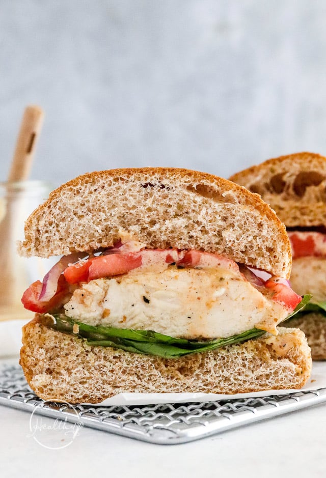 grilled chicken sandwich cut in half, dripping with sauce