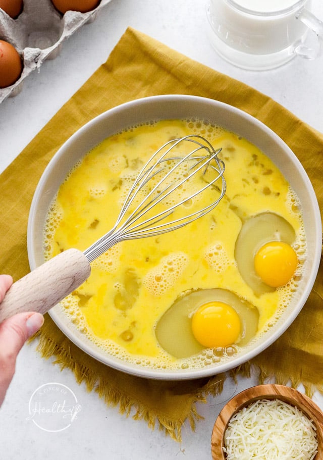 hand whisking eggs in a bowl