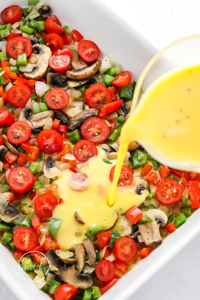 pouring eggs over vegetables in a casserole dish