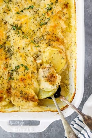 scalloped potatoes in casserole dish with serving spoon