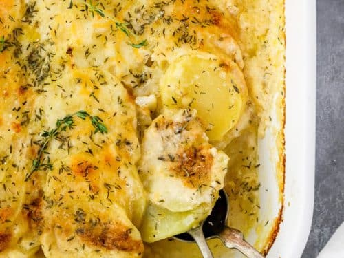 scalloped potatoes in casserole dish with serving spoon