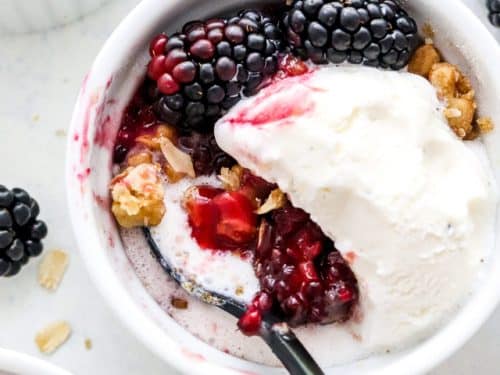 Blackberry crisp a la mode in white dish with spoon