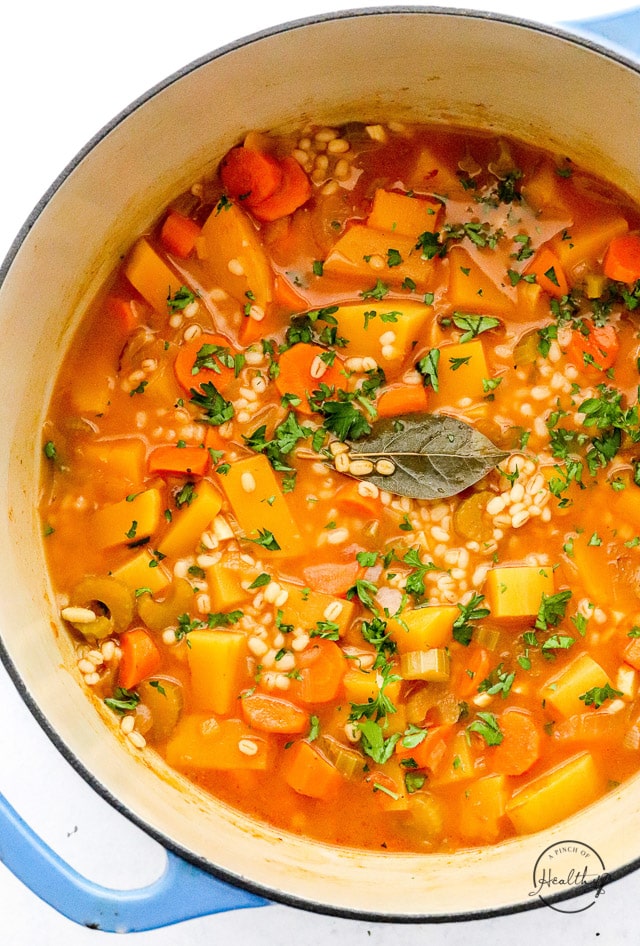 vegetable barley soup in a big pot with bay leaves on top