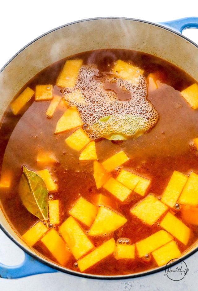 simmering soup with butternut squash and bay leaves