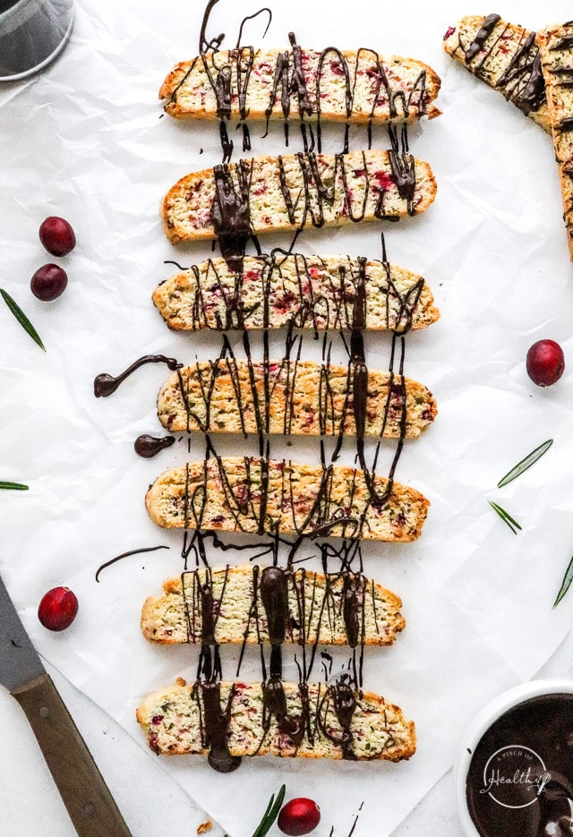 drizzling Christmas biscotti with dark chocolate on parchment paper