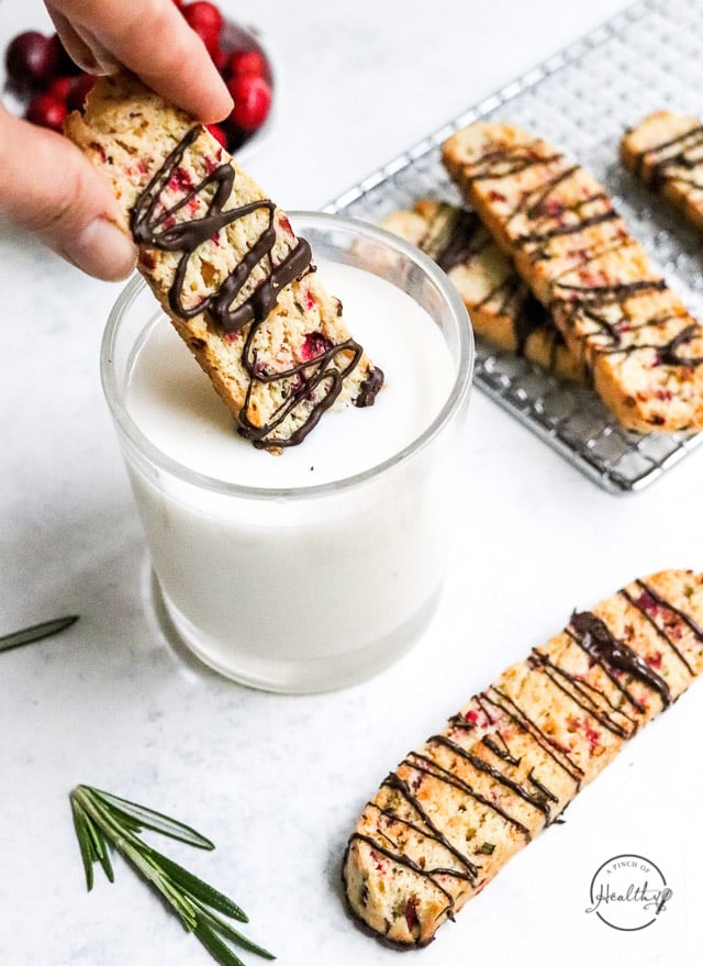 hand dunking Christmas biscotti into glass of milk