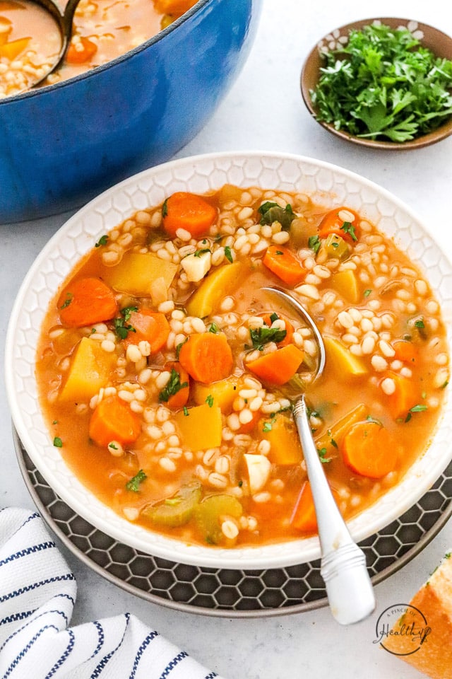 vegetable barley soup in a bowl with a spoon