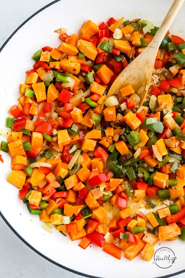 cooking veggies in a pan with wooden spoon
