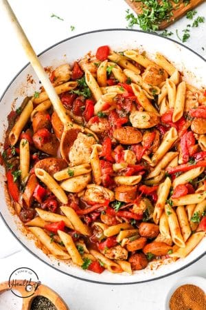 cooking jambalaya pasta in a pan with wooden spoon