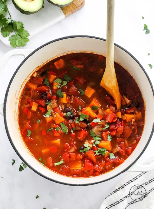 sweet potato black bean chili in a pot with wooden spoon