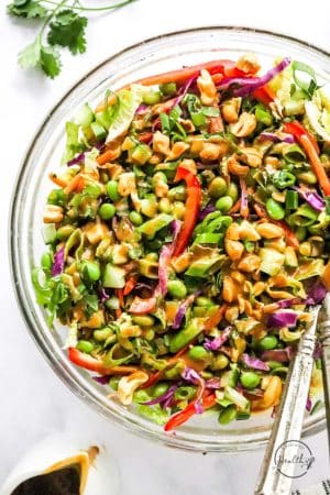 Thai Salad with peanut dressing in serving bowl on white surface