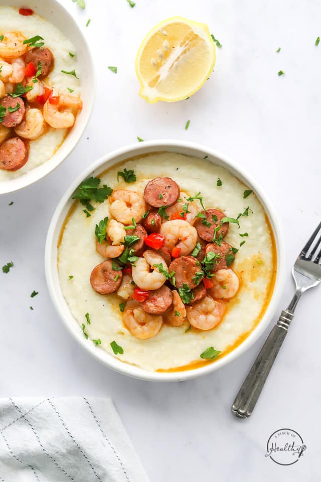 cajun shrimp and grits in a white bowl with spoon