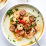 cajun shrimp and grits in a white bowl with spoon