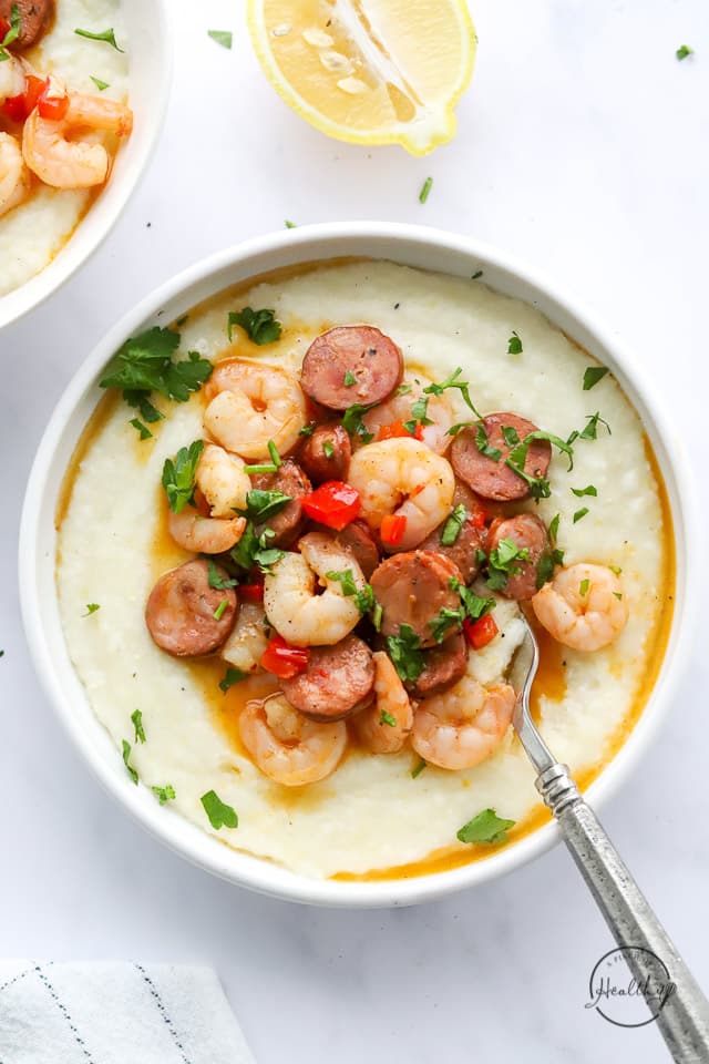 cajun shrimp and grits in a white bowl with spoon