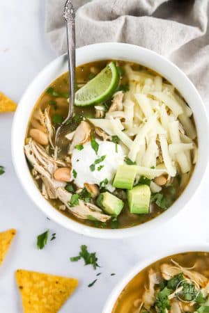 Instant Pot white chicken chili in a bowl with cheese, avocado and lime
