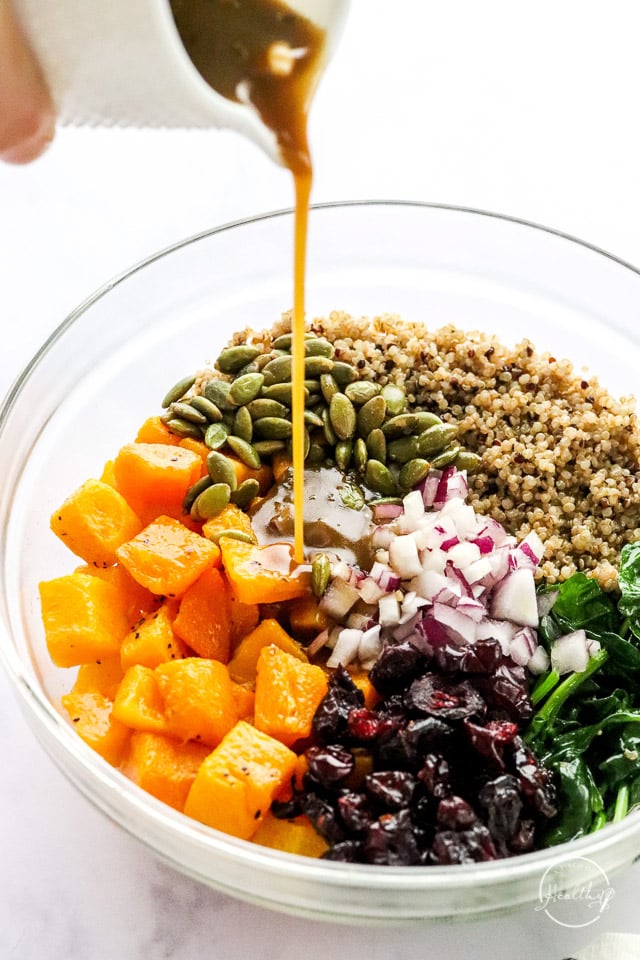 pouring vinaigrette dressing on quinoa salad