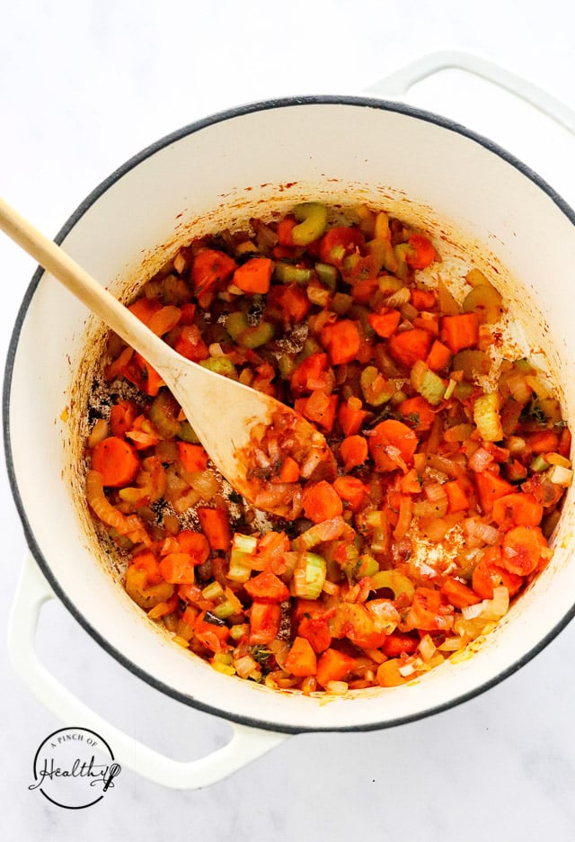 adding tomato paste and thyme to veggies