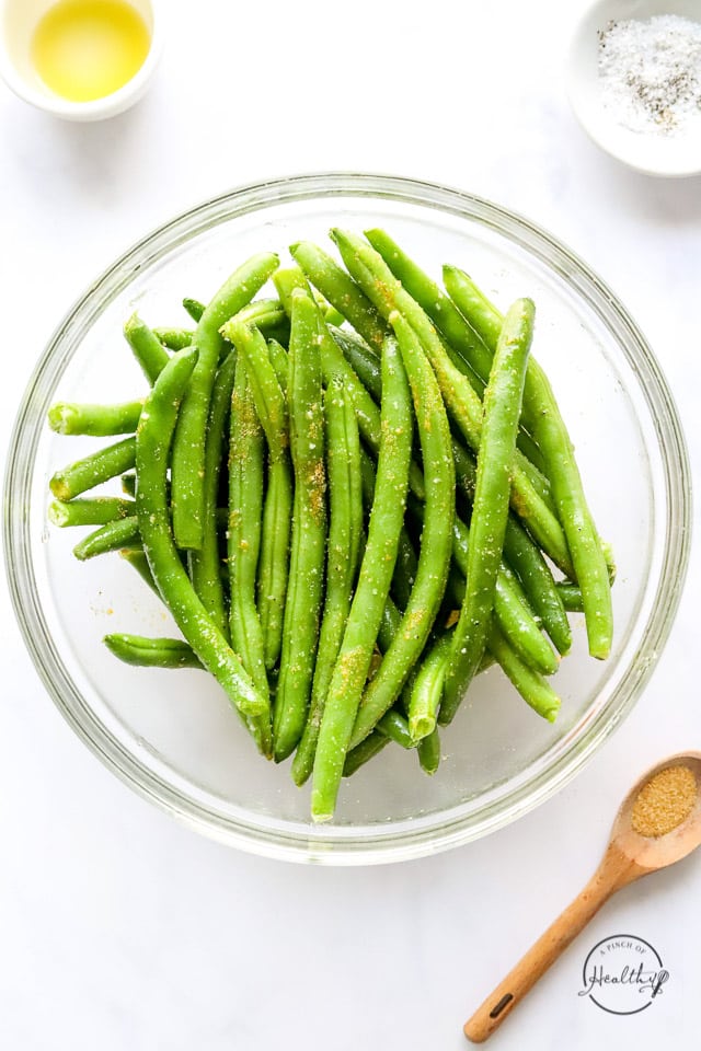 raw seasoned green beans in a mixing bowl