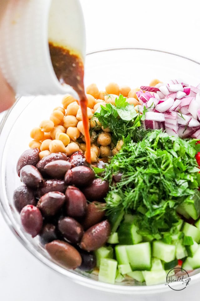 pouring dressing over chickpea salad ingredients