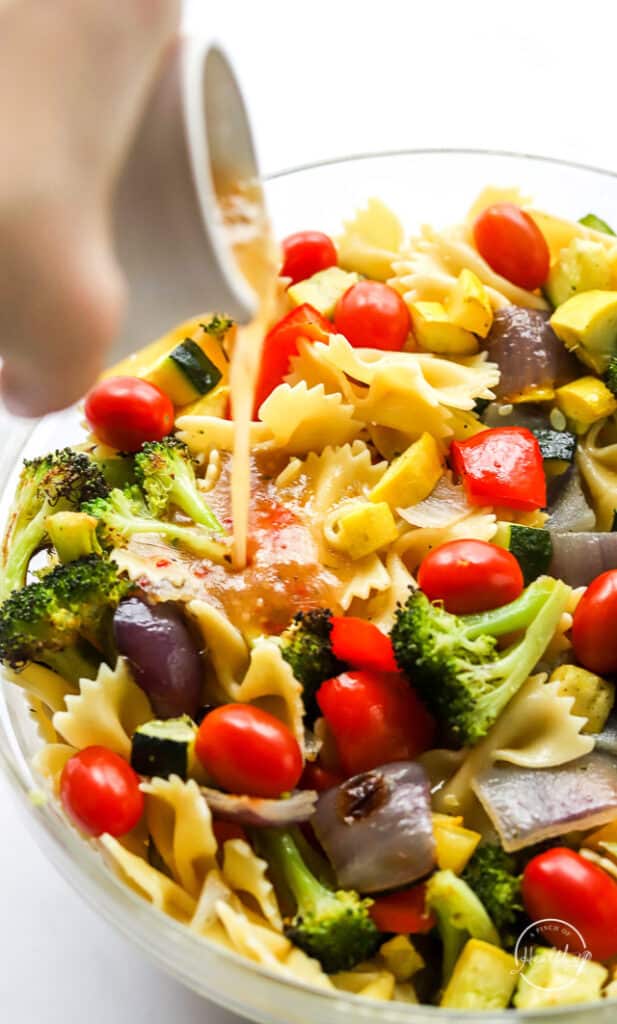 pouring dressing on Italian pasta salad