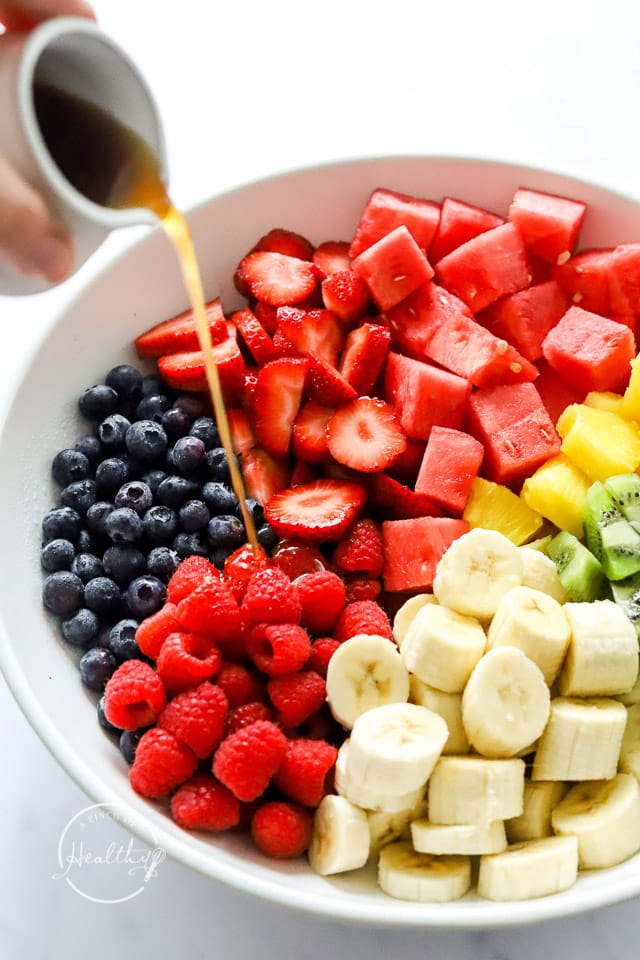 pouring dressing on fruit salad