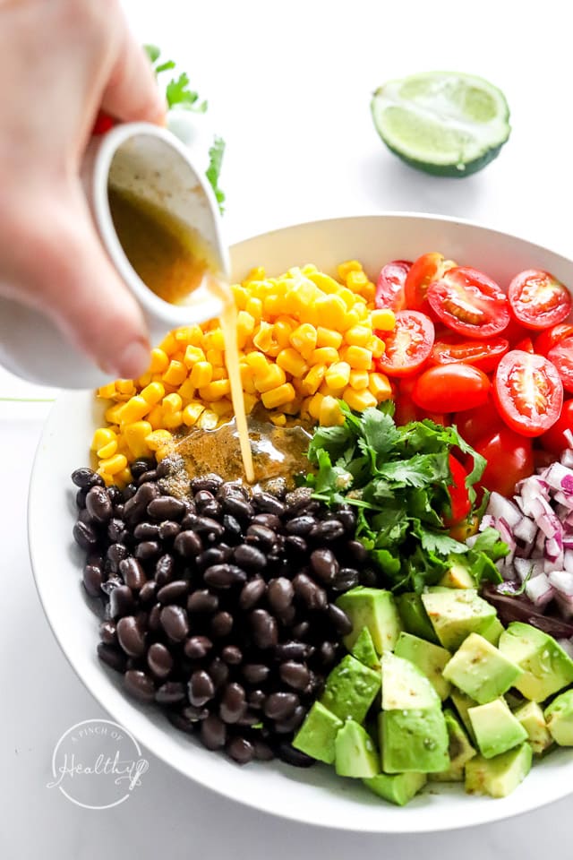 pouring dressing on black bean salad ingredients