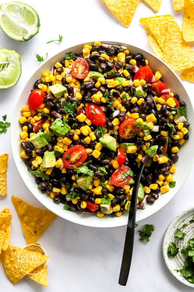 black bean salad in a white serving bowl with spoon