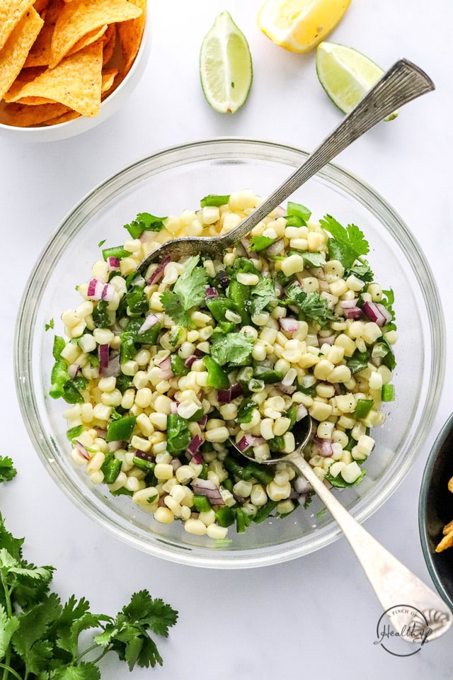 Corn salsa in a bowl with serving spoons