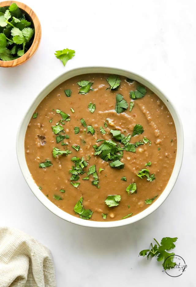 Instant Pot refried beans in a serving bowl with chopped cilantro on top