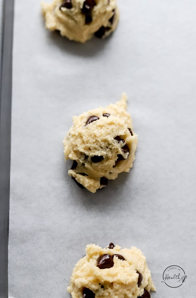 vegan chocolate chip cookie dough scooped on a lined baking sheet