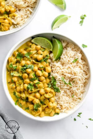 Chickpea Curry with rice in a white bowl with lime slices