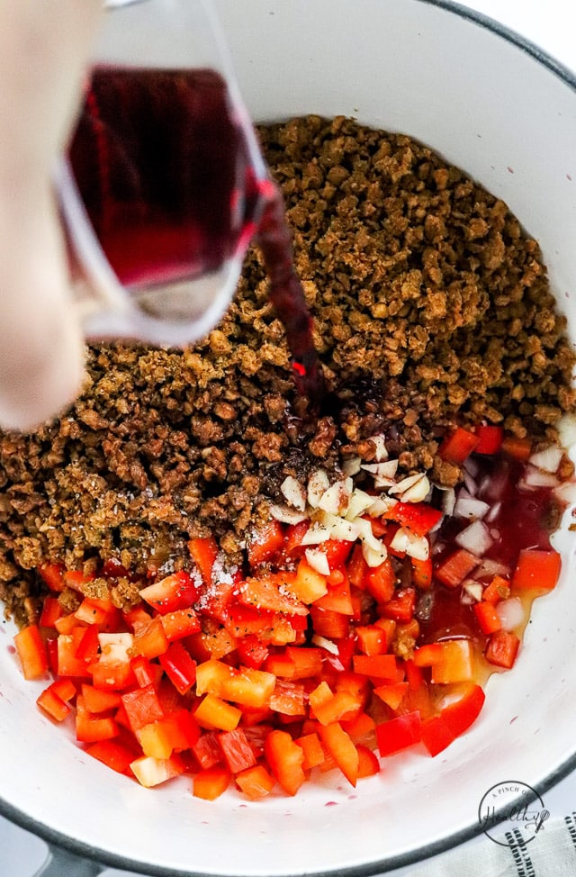 adding liquid to veggies and vegan meat in a pot