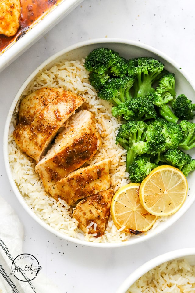 baked chicken breast on a plate with rice and veggies