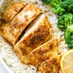baked chicken breast with rice, veggies and lemon slice on a plate