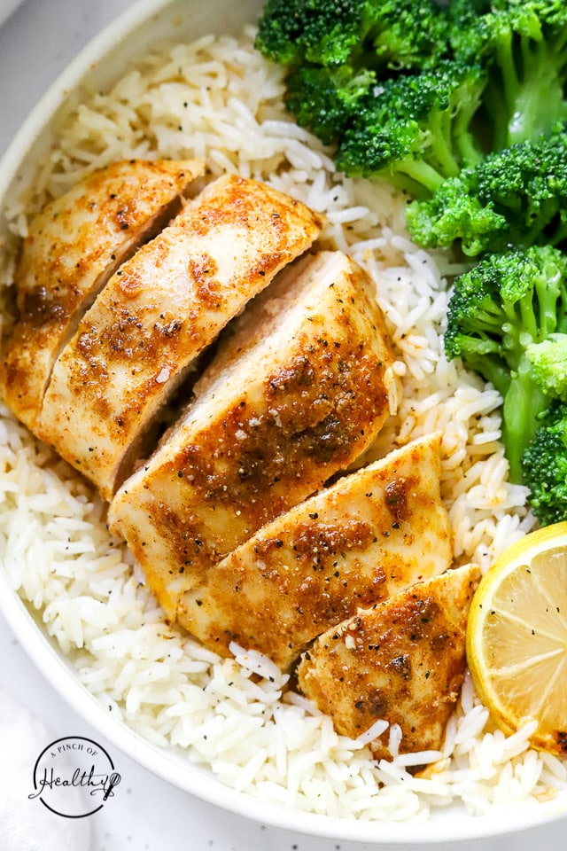baked chicken breast with rice, veggies and lemon slice on a plate