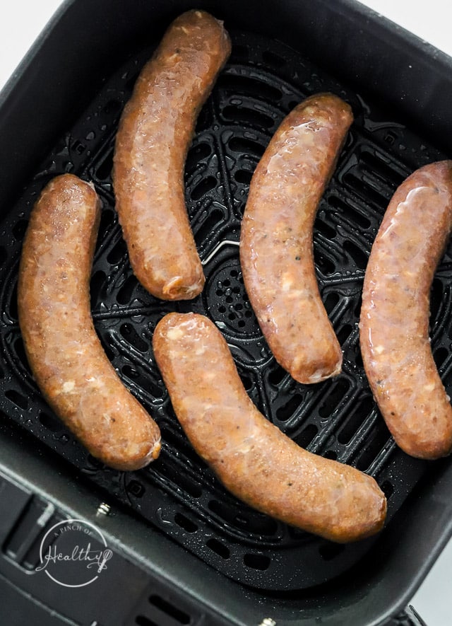 uncooked bratwurst in air fryer basket
